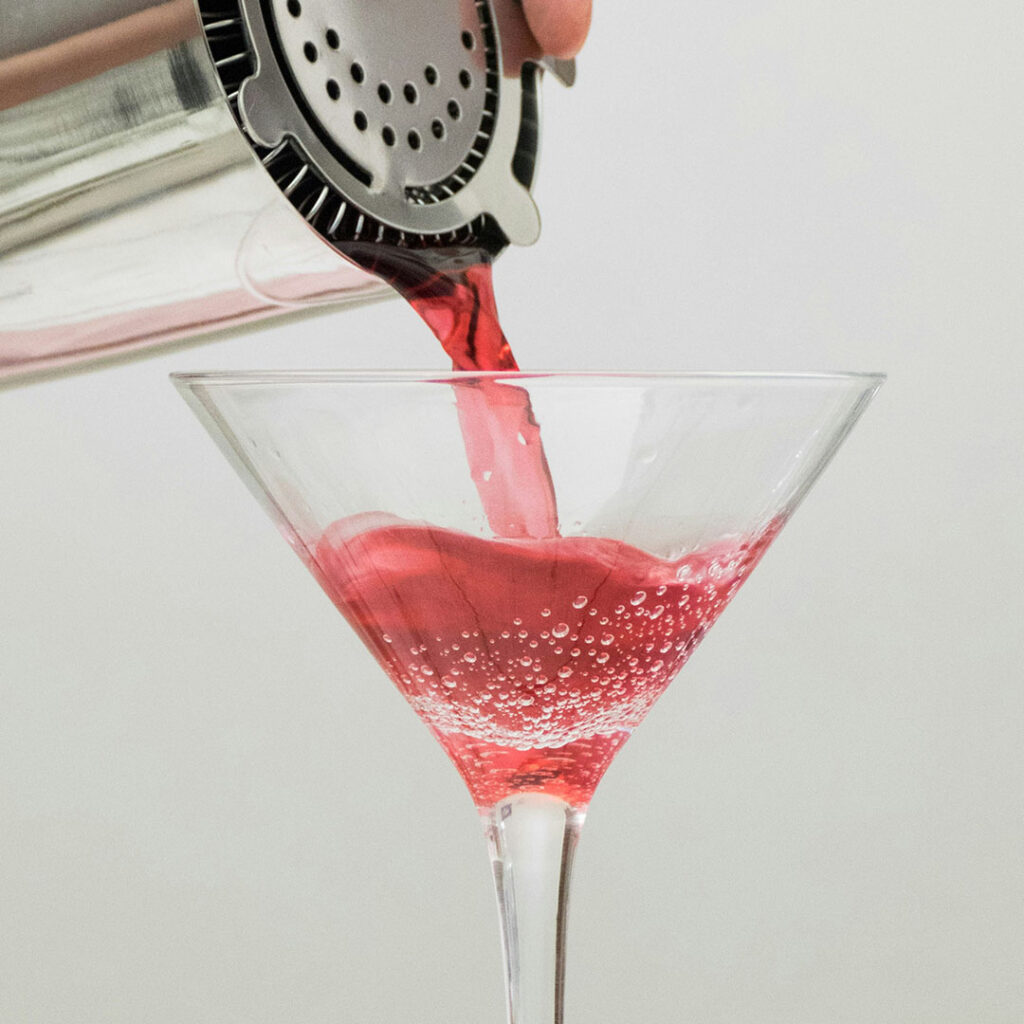 Jak zrobić koktajl cosmopolitan? 45 ml wódki cytrynowej, 15 ml Triple Sec, 30 ml soku żurawinowego i 10 ml świeżego soku z limonki